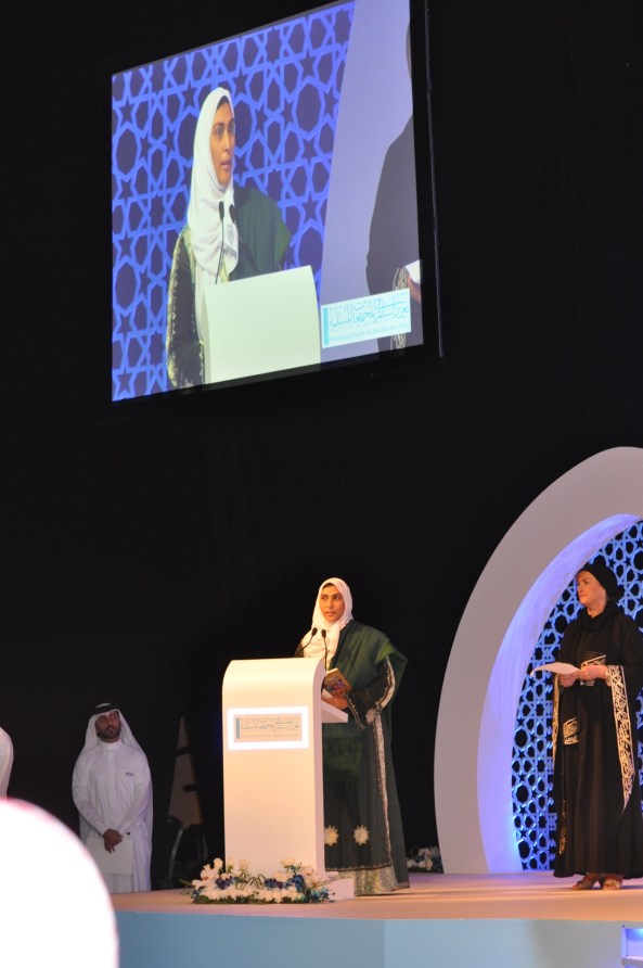 Nimah at Peace Forum Reading poem closing  wide shot with screen and Judge Marlyn- UK - Abu Dhabi  March 10 2014  cropped   1
